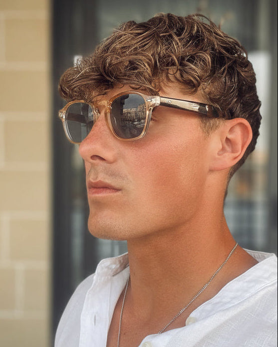 Man wearing sunglasses and a white shirt with a blur background